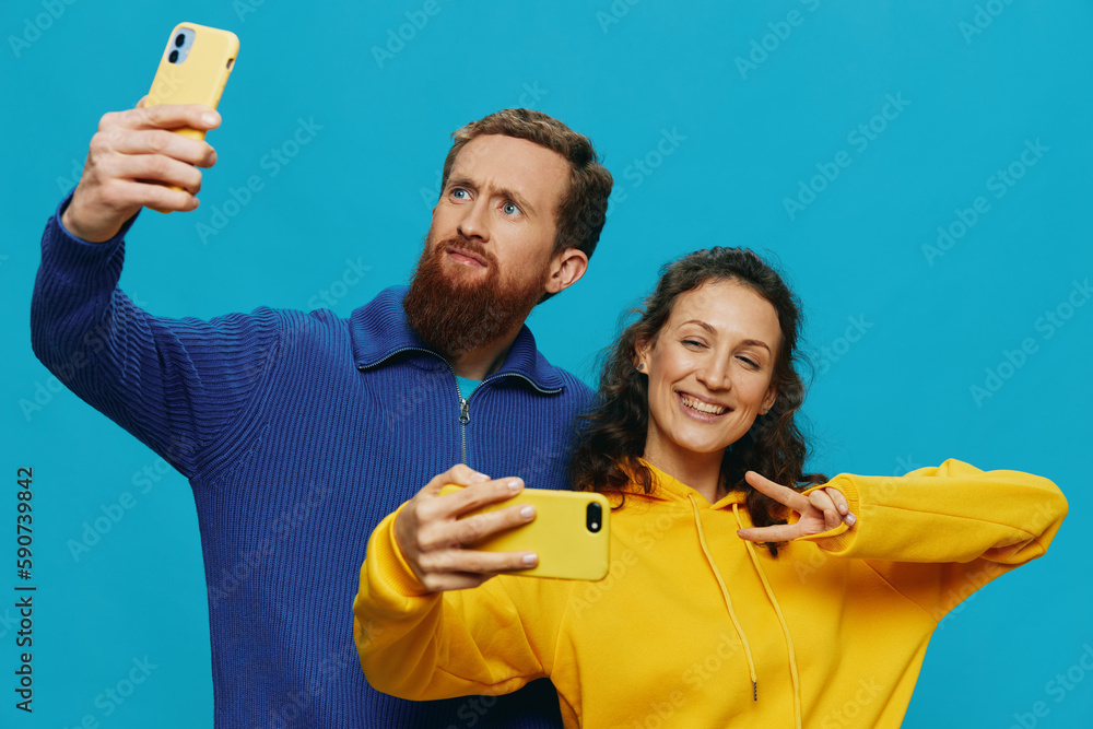 Woman and man funny couple with phones in hand taking selfies crooked smile fun, on blue background. The concept of real family relationships, talking on the phone, work online. Woman and man funny couple with phones in hand taking selfies crooked smile fun, on blue background. The concept of real family relationships, talking on the phone, work online.