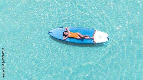 Obraz na płótnie Asian woman in bikini sleep and relax on paddle board on the beach w salonie