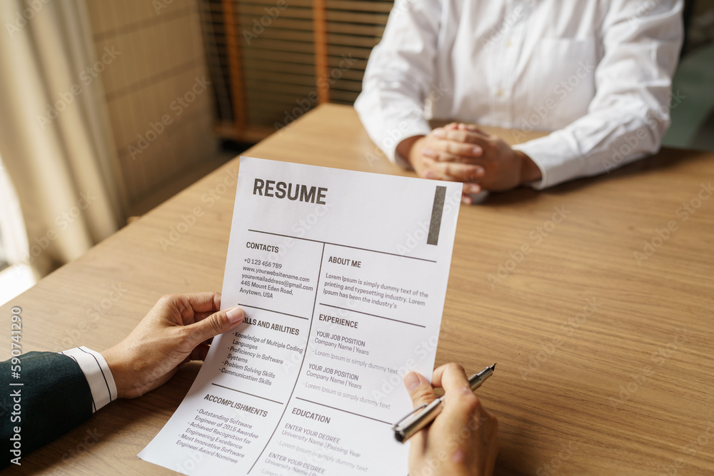 Examiner reading a resume during job interview at office Business and human resources concept Examiner reading a resume during job interview at office Business and human resources concept