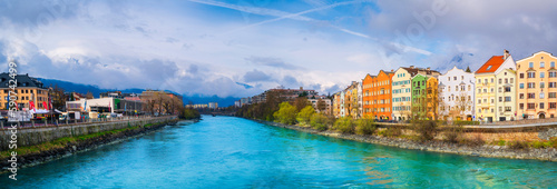 Innsbruck city skyline on a April day with vibrant colorful houses, the snowy Alps mountains, foggy cloudscape, the green Inn River in historic landmark town of Tyrol in western Austria