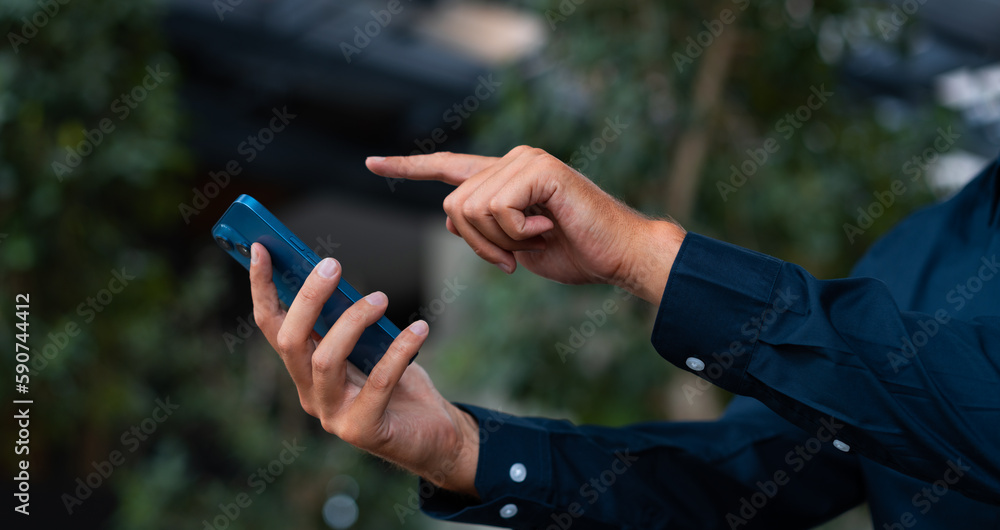 Businessman finger touch smartphone on blurred trees background