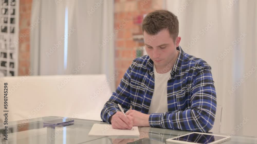 Young Casual Man Working on Documents, Doing Paperwork Young Casual Man Working on Documents, Doing Paperwork