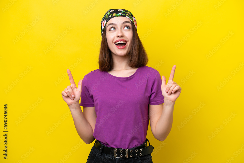 Young Ukrainian woman isolated on yellow background surprised and pointing up Young Ukrainian woman isolated on yellow background surprised and pointing up