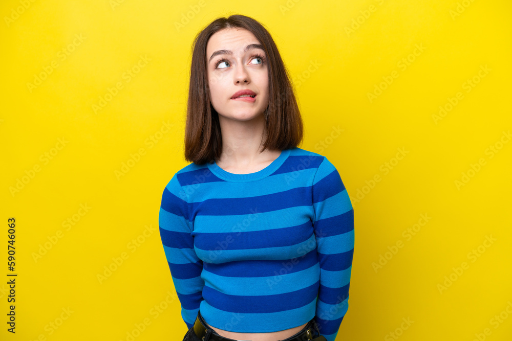 Young Ukrainian woman isolated on yellow background and looking up Young Ukrainian woman isolated on yellow background and looking up