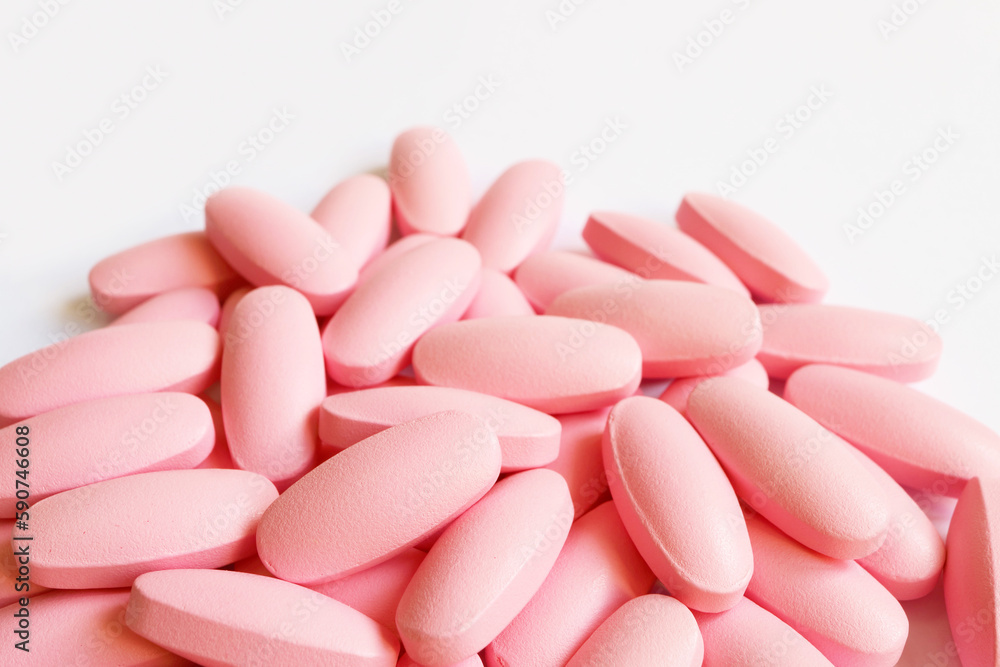 Heap of pastel pink supplement pills on white background with copy space