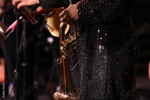Photography A golden flugelhorn in the lowered hand of an artist on the stage of a festive c
