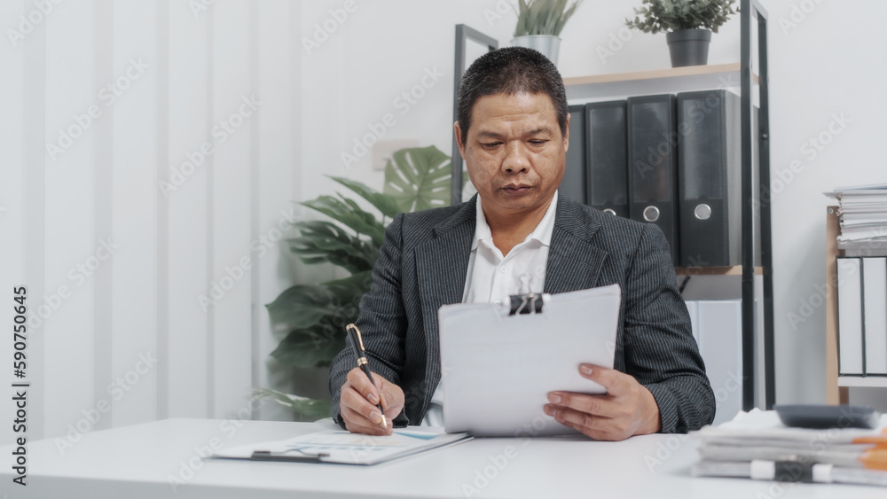 Fototapeta premium Reading paper charts, Elderly Old Senior Asian male businessman wearing formal suit ,confident professional bookkeeper doing bookkeeping, lawyer, stock market trader or broker.
