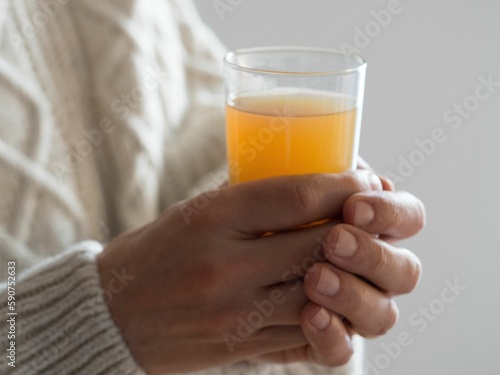 Closeup shot of a person holding a cup filled with an orange beverage