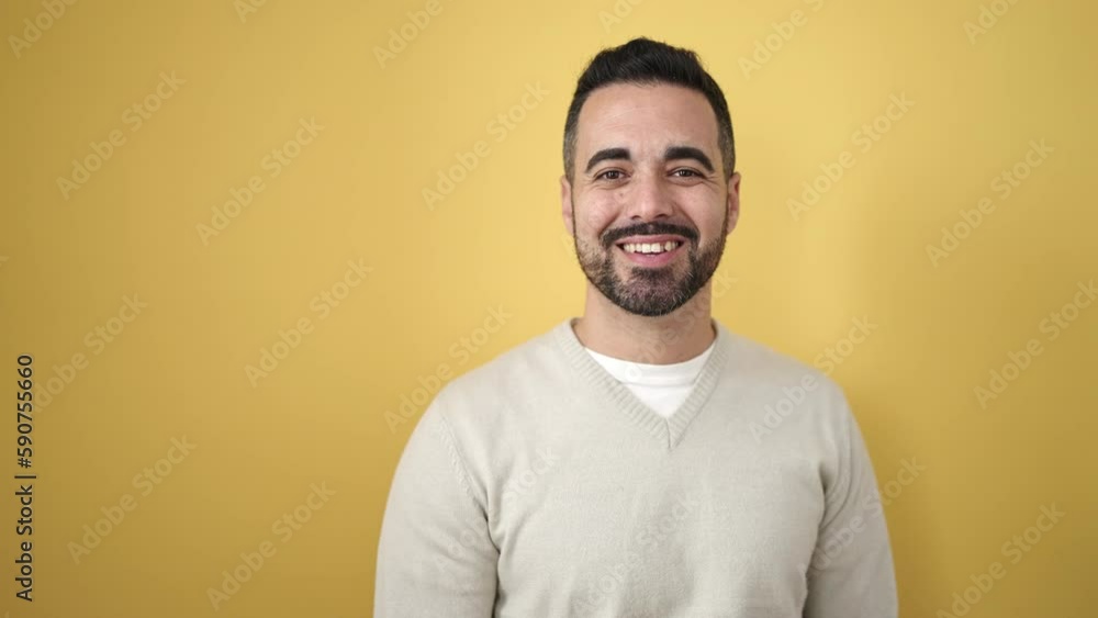 Young hispanic man smiling confident pointing with fingers to the side over isolated yellow background Young hispanic man smiling confident pointing with fingers to the side over isolated yellow background
