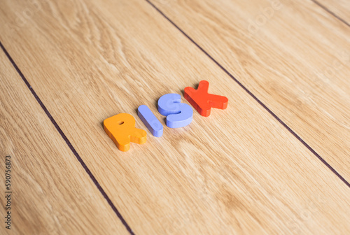Colorful cubes lettering word "RISK" on wooden background. 