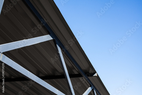 Iron structure  roof covered with corrugated aluminum sheets on metal supports  against a clear blue sky during the day.