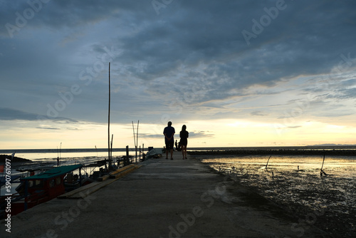 Beautiful sunset at Kampung kuala Kuar Jawa fishing village, Alor setar, Kedah. Silhouette of a couple standing at the pier.