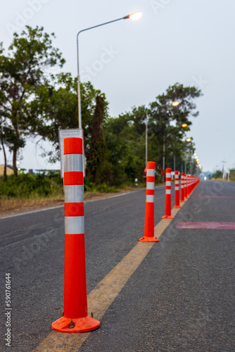 A low-angle view of many reflective orange plastic poles set up as a sign to prevent oncoming traffic.