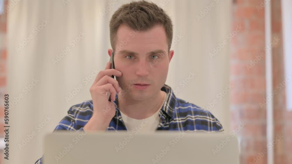 Close up of Young Man Talking on Phone at work Close up of Young Man Talking on Phone at work
