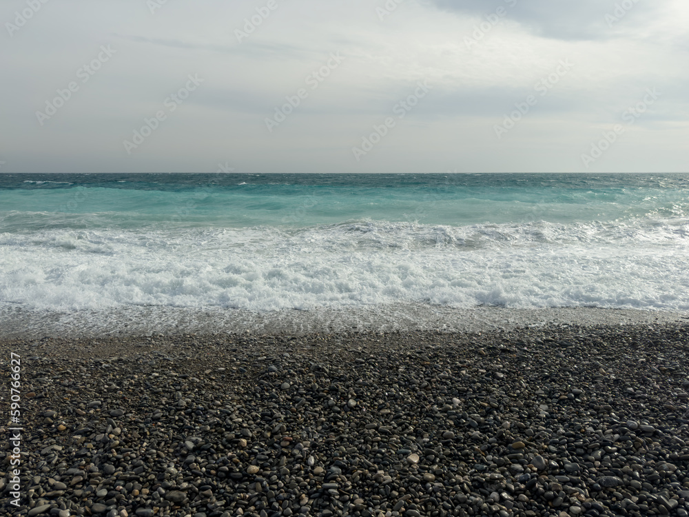 Pebble beach of Nice, France with azure waves of mediterranean sea Pebble beach of Nice, France with azure waves of mediterranean sea