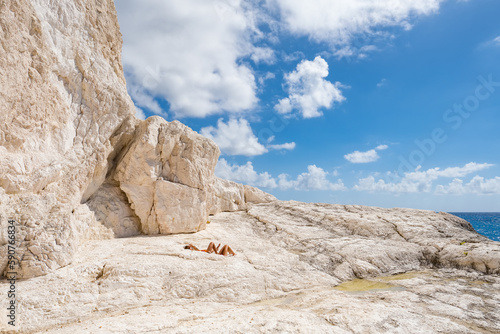 Fototapeta Naklejka Na Ścianę i Meble -  Couple sunbathe on the limestone rocky coast of Zakynthos island, Greece
