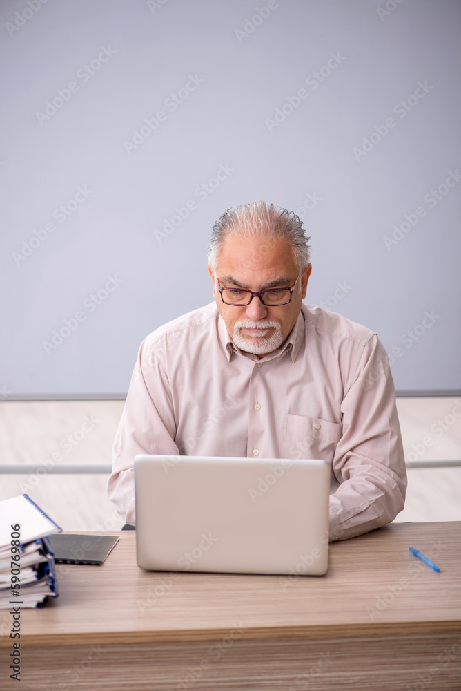 Old male teacher in front of whiteboard Old male teacher in front of whiteboard