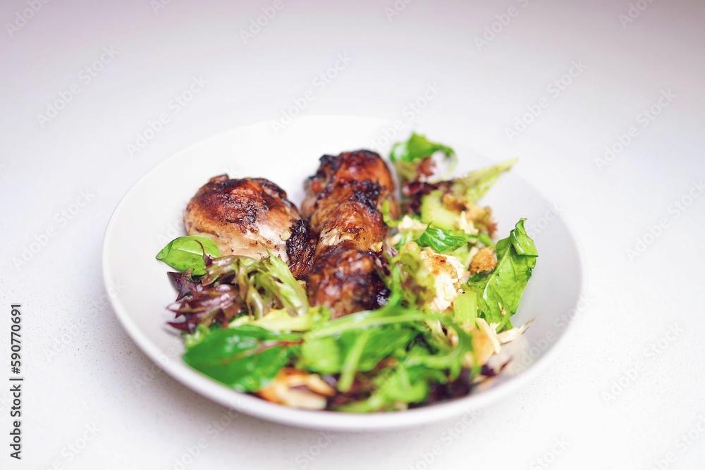 High angle closeup shot of a rustic chicken meal served with a salad in a white bowl High angle closeup shot of a rustic chicken meal served with a salad in a white bowl
