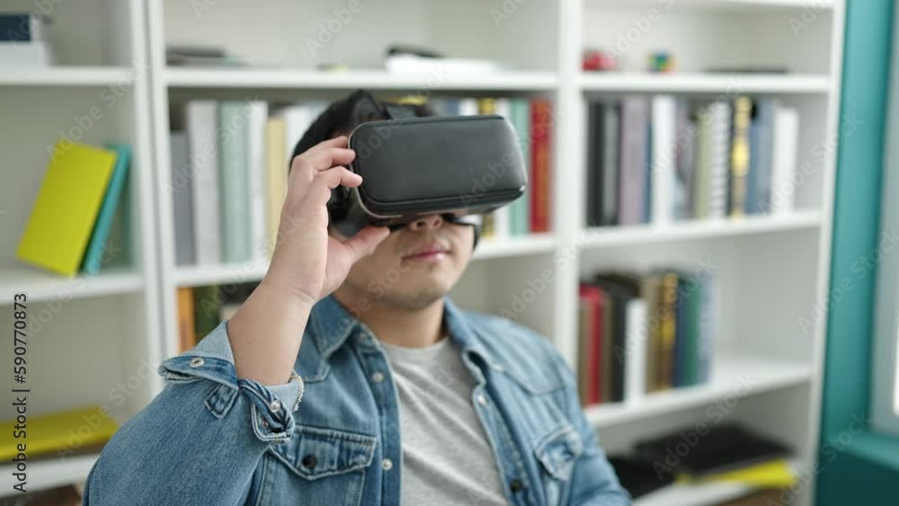 Young chinese man student smiling confident using virtual reality glasses at library university Young chinese man student smiling confident using virtual reality glasses at library university