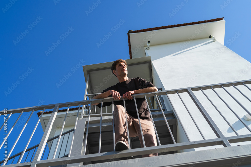 Low angle of young man standing beside apartment complex on his neighborhood