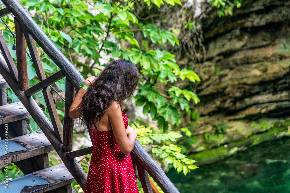 Naklejka premium Tourist in the stairway of the subway cenote Saamal of chichén itzá is in the Mayan jungle hacienda of the Yucatan Peninsula in Mexico, it is an ideal place for vacation.