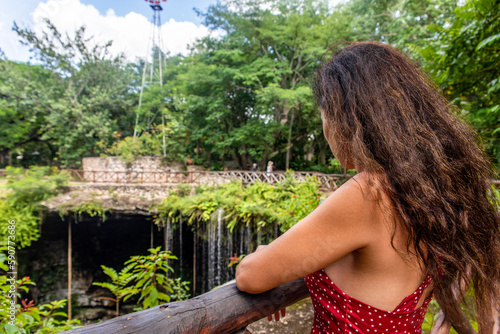 Tourist woman looking at the mouth of the subway cenote Saamal of chichén itzá in the Mayan jungle hacienda of the Yucatan Peninsula in Mexico, this is an ideal place for summer vacations. photo