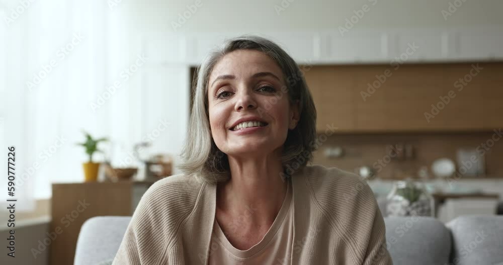 Positive pretty grey haired woman talking on video conference call, listening, nodding, speaking, laughing, explaining with hand gestures, enjoying Internet communication. Head shot portrait Positive pretty grey haired woman talking on video conference call, listening, nodding, speaking, laughing, explaining with hand gestures, enjoying Internet communication. Head shot portrait