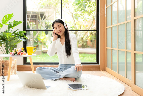 Young smiling woman happy listen music for chill and relax in summer holiday. Lifestyle girl using laptop for entertainment in living room at home. Nature garden background. Lifestyle Concept