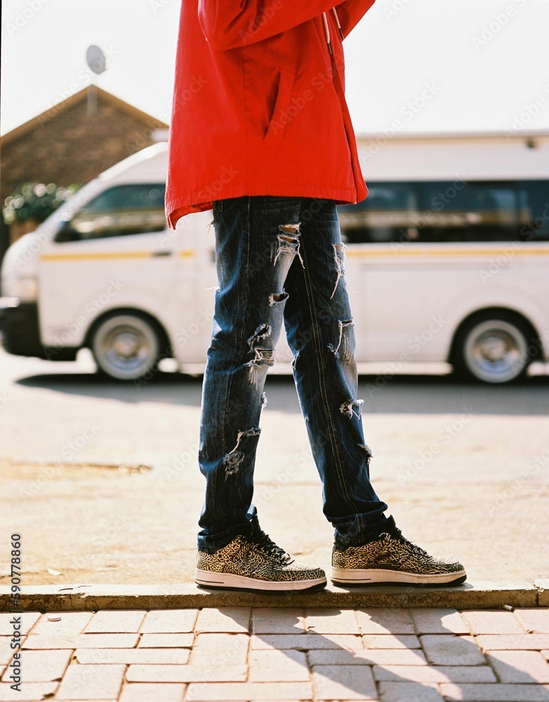 Fototapeta premium Vertical shot of a cool kid walking in the street in Johannesburg, South Africa