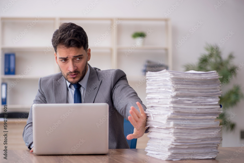Young male employee and too much work in the office Young male employee and too much work in the office