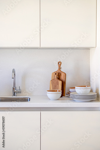 interior close-up on dairy minimalistic kitchen cabinet fronts  sink  wooden cutting boards  plates and bowls