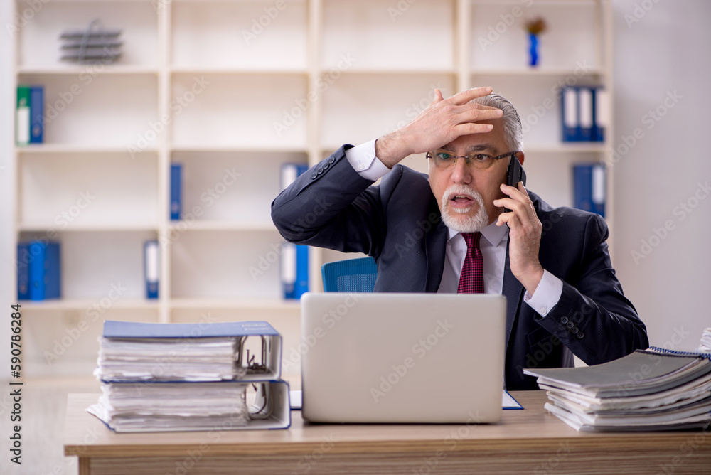 Old male employee sitting at workplace Old male employee sitting at workplace