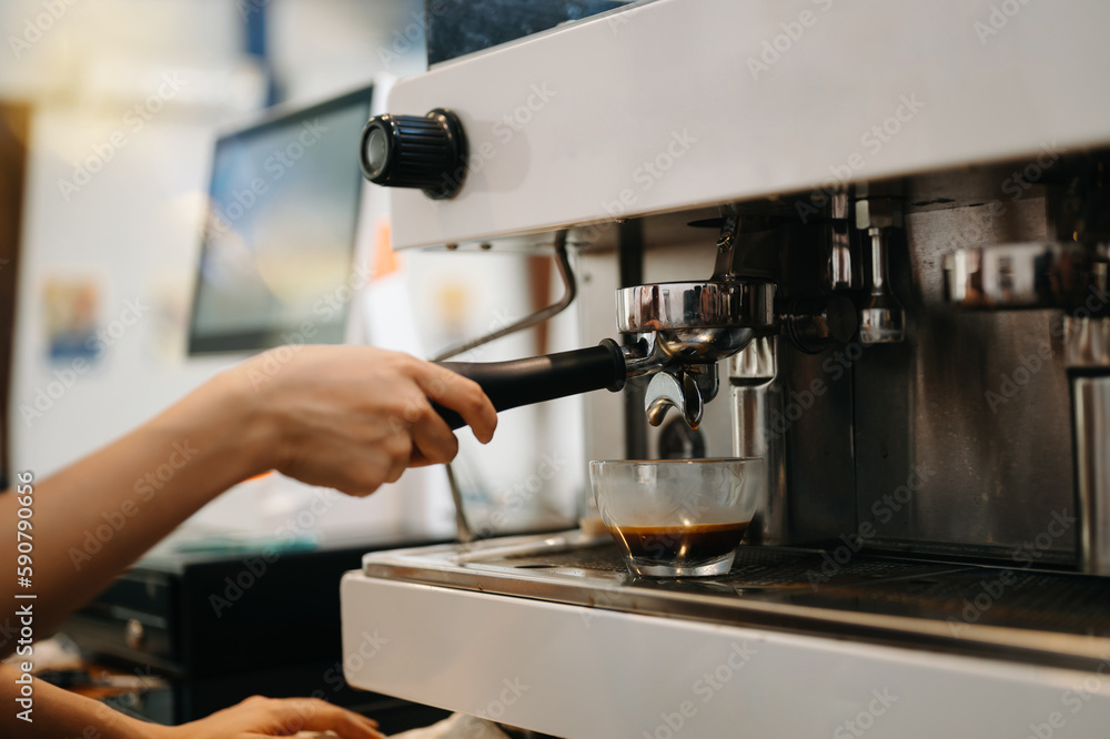 Cup and professional espresso machine pouring fresh coffee into a glass cup at cafe