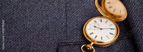 Golden pocket watch on the background of a man's suit. Retro style and vintage fashion. 