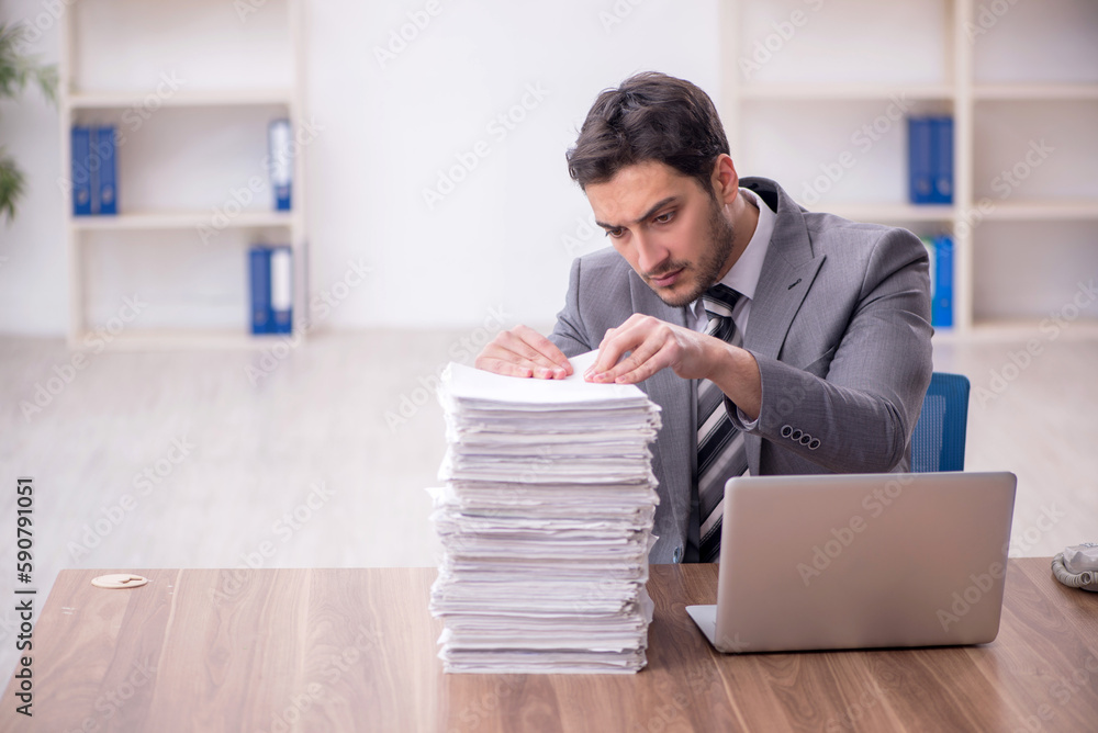 Obraz premium Young male employee and too much work in the office