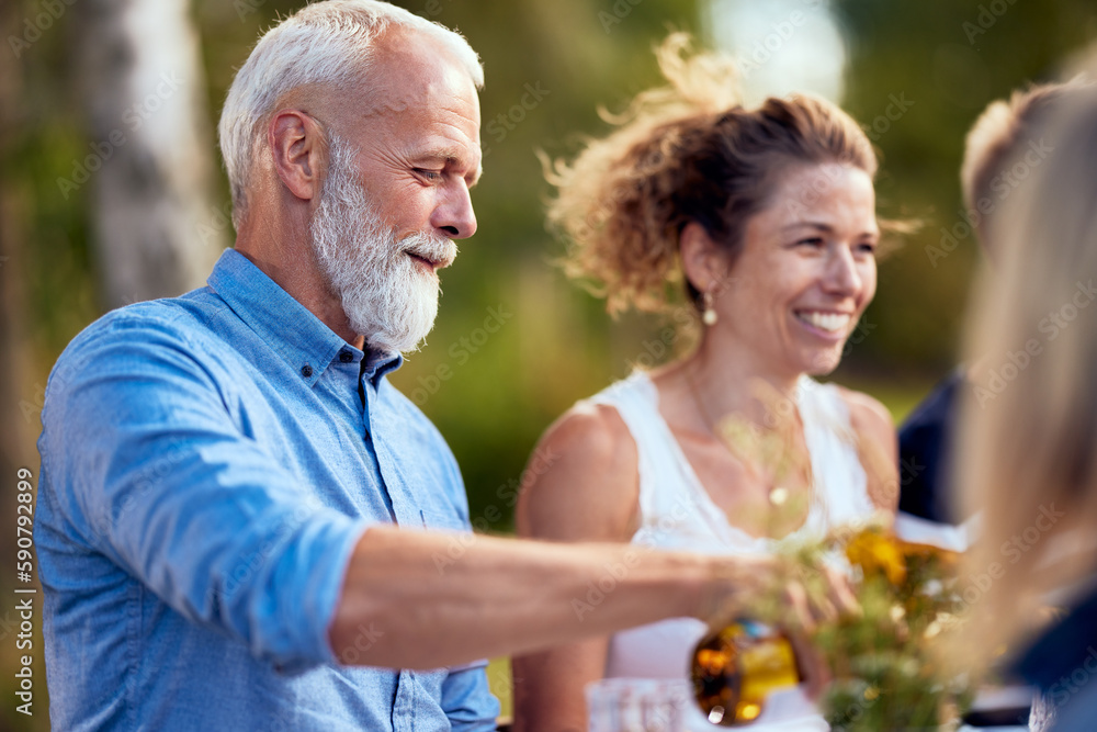 Man pouring friends wine outdoors Man pouring friends wine outdoors
