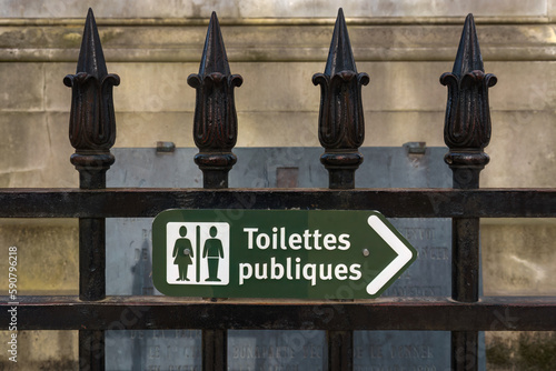 Green public toilet sign in French on a fence
