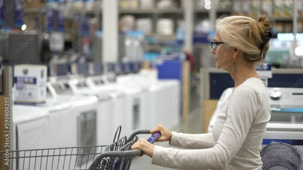 Slow motion of mature elderly woman pushing shopping cart in hardware