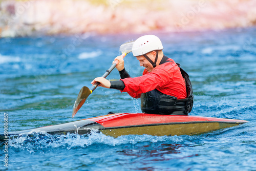 Man in red kayak sails mountain river. Whitewater kayaking, extreme sport rafting © Parilov