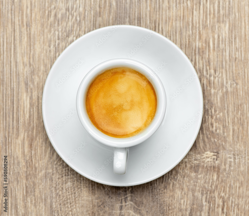 White cup of espresso coffee with creams on a wooden table, top view White cup of espresso coffee with creams on a wooden table, top view