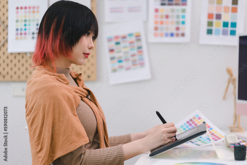 Young graphic designer using a tablet and stylus pen while sitting at her desk in office. Young graphic designer using a tablet and stylus pen while sitting at her desk in office.