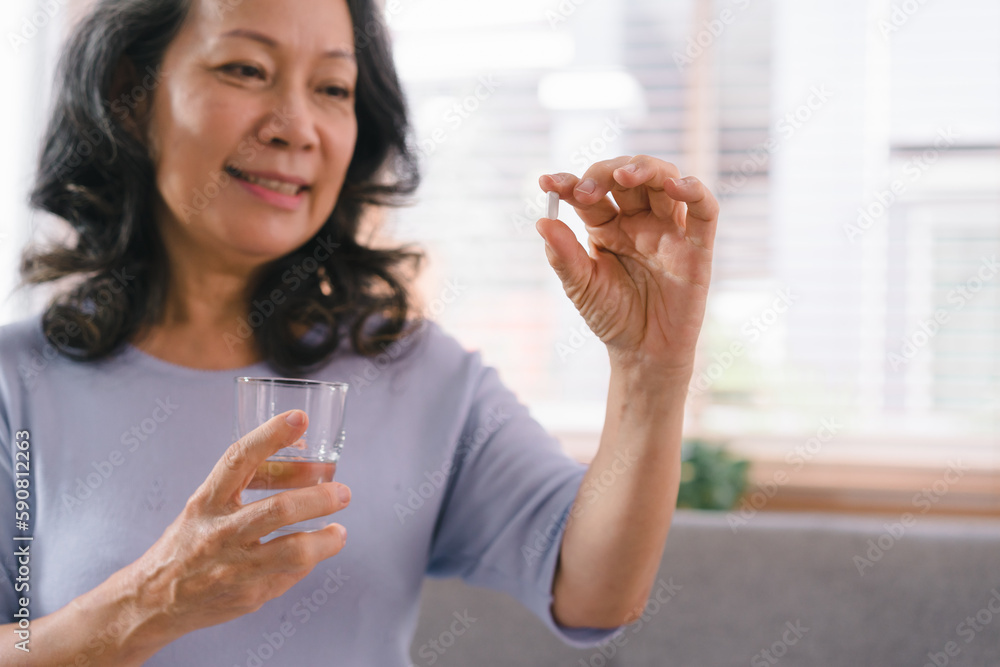 Close-up of a happy senior lady holding a glass of water and taking a pill. The smiling elderly woman is using supplements.Supplements, vitamins, and healthy lifestyle concept. Selective focus Close-up of a happy senior lady holding a glass of water and taking a pill. The smiling elderly woman is using supplements.Supplements, vitamins, and healthy lifestyle concept. Selective focus