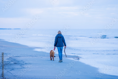 woman walking on the beach with dog