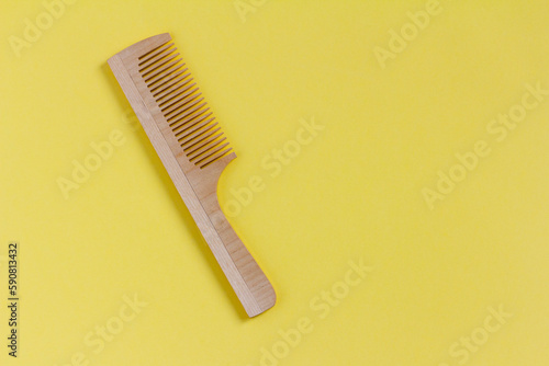 Wooden comb on a yellow background  top view.