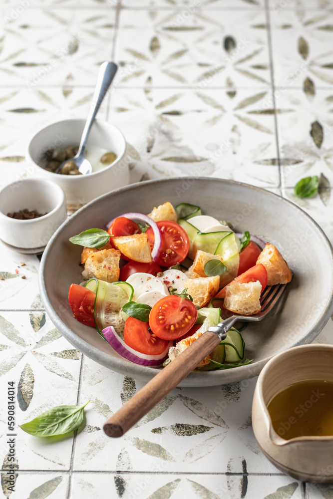 Traditional italian tomato salad panzanella with mozzarella, capers, red onion, croutons, cucumbers and basil. Summer salad on printed tile background with copy space Traditional italian tomato salad panzanella with mozzarella, capers, red onion, croutons, cucumbers and basil. Summer salad on printed tile background with copy space