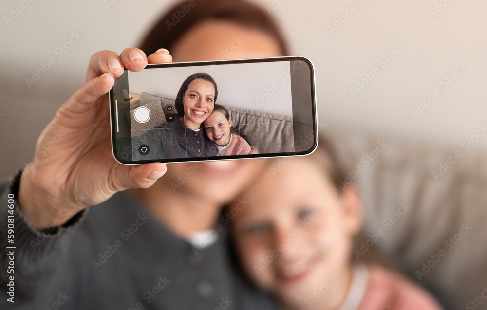 Happy teen european girl and millennial female take selfie on smartphone screen in living room
