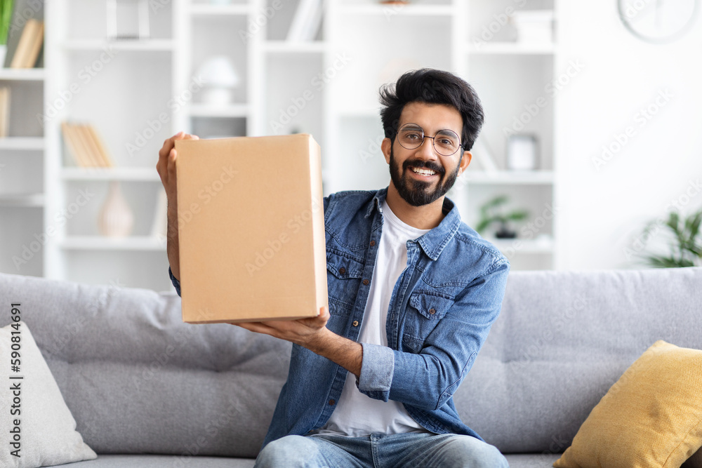 Handsome Young Indian Man Demonstrating Cardboard Box With Delivery At Home Handsome Young Indian Man Demonstrating Cardboard Box With Delivery At Home