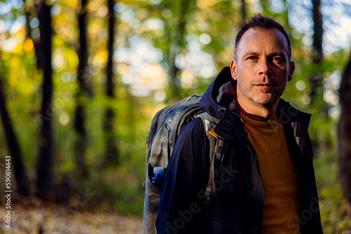 Handsome middle-aged man standing in the forest and looking at the camera