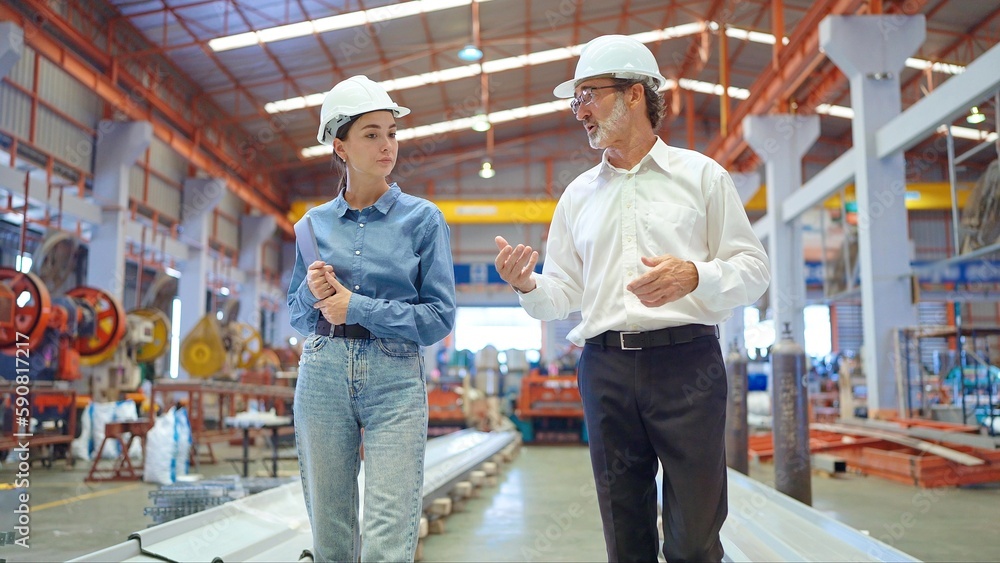 Two professional engineer man and woman manager leader wearing helmet and walking in factory talking and discussing for work Two professional engineer man and woman manager leader wearing helmet and walking in factory talking and discussing for work