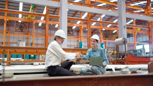 Two engineer manager leader and woman assistant holding laptop and shaking hands for making together after processes order at metal factory